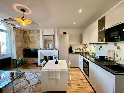 a kitchen with white cabinets and a table in it at Cosy appartement Bordeaux centre in Bordeaux