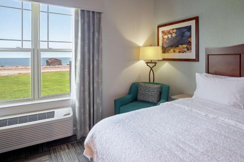 a hotel room with a bed and a chair and a window at Hampton Inn Duluth-Canal Park in Duluth