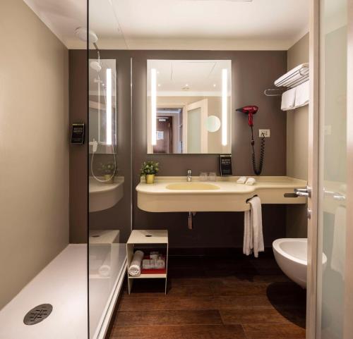 a bathroom with a sink and a toilet and a mirror at Best Western Plus City Hotel in Genova