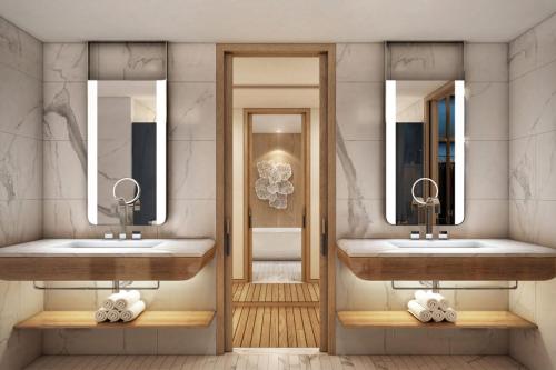 La salle de bains est pourvue de 2 lavabos et de 2 miroirs. dans l'établissement The St Regis Al Mouj Muscat Resort, à Mascate