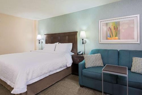 une chambre d'hôtel avec un lit et un canapé bleu dans l'établissement Hampton Inn White Plains/Tarrytown, à Elmsford