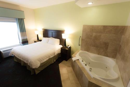 a hotel room with a bed and a bath tub at Hampton Inn & Suites Middlebury in Middlebury