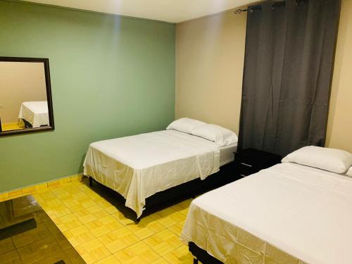 a room with two beds and a mirror in it at La Casita in San Pedro Sula