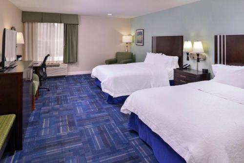 a hotel room with two beds and a desk at Hampton Inn Eugene in Eugene