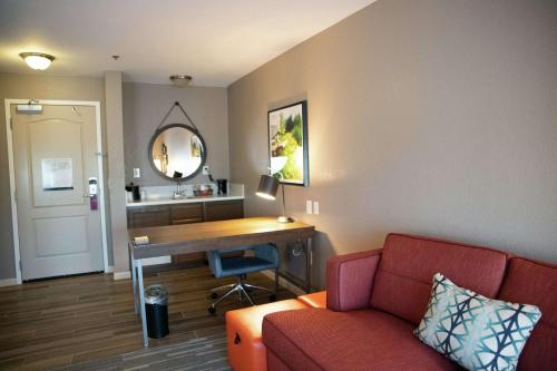 Camera con divano, scrivania e specchio. di Hampton Inn & Suites Fresno a Fresno