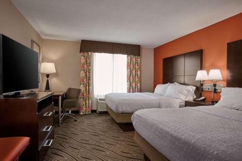 a hotel room with two beds and a flat screen tv at Hampton Inn Evansville Airport in Evansville