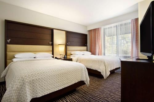 Habitación de hotel con 2 camas y TV de pantalla plana. en Embassy Suites by Hilton Fayetteville Fort Bragg, en Fayetteville