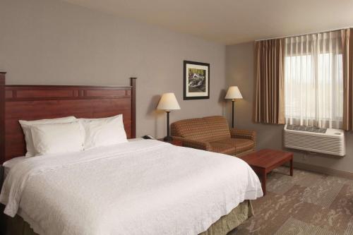 um quarto de hotel com uma cama e uma cadeira em Hampton Inn Kalispell em Kalispell