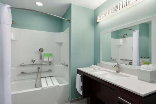 a bathroom with a tub and a sink and a mirror at Home2Suites by Hilton Florence in Florence