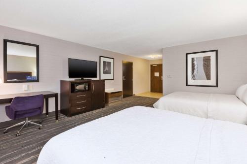 a hotel room with two beds and a desk and a tv at Hampton Inn and Suites Flint/Grand Blanc in Flint