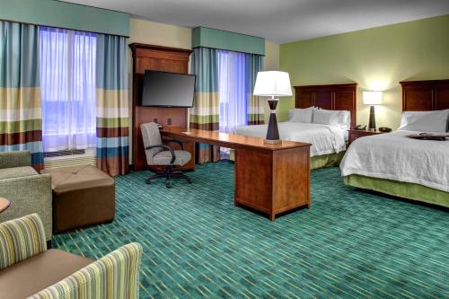 West Dixie BendにあるHampton Inn and Suites Coconut Creekのベッド2台とデスクが備わるホテルルームです。