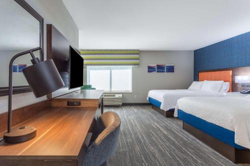 a hotel room with two beds and a desk with a television at Hampton Inn Sioux Falls in Hayward Addition