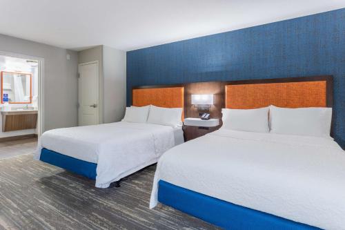 a hotel room with two beds and a blue wall at Hampton Inn Sioux Falls in Hayward Addition