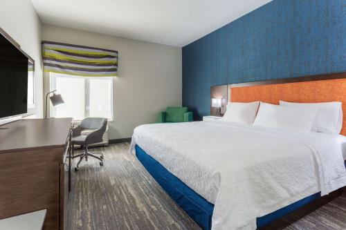 a hotel room with a large bed and a desk at Hampton Inn Sioux Falls in Hayward Addition