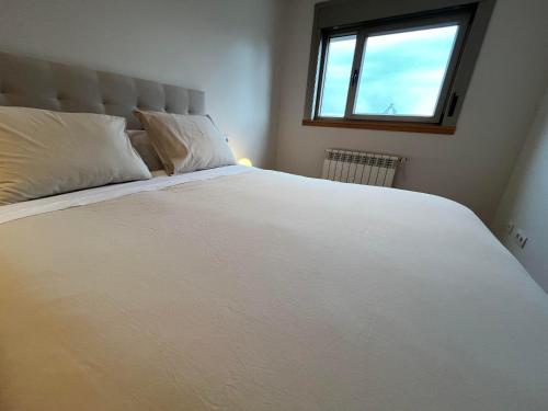 ein großes weißes Bett in einem Schlafzimmer mit Fenster in der Unterkunft Coruña House in A Coruña