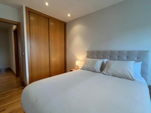 ein Schlafzimmer mit einem großen weißen Bett und einem Holzschrank in der Unterkunft Coruña House in A Coruña