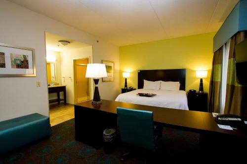 a hotel room with a bed and a desk with a lamp at Hampton Inn Fayetteville in Fayetteville