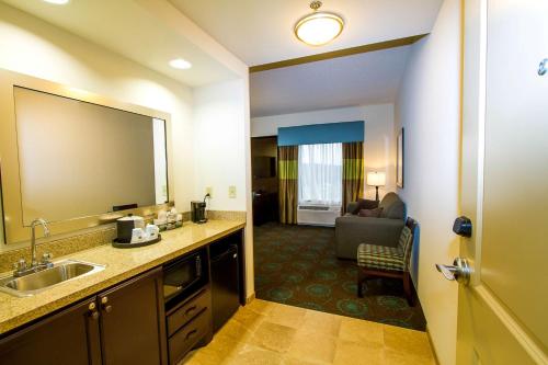 ein Hotelzimmer mit einem Waschbecken und einem Wohnzimmer in der Unterkunft Hampton Inn Fayetteville in Fayetteville