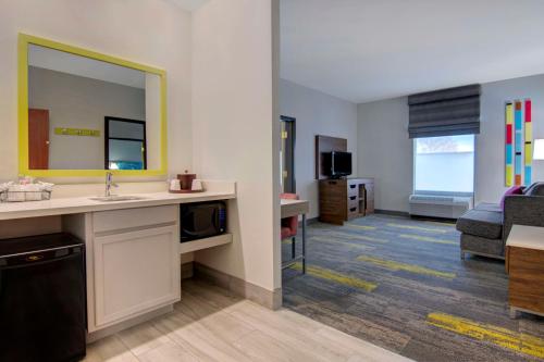 a bathroom with a sink and a living room at Hampton Inn Fayetteville in Fayetteville
