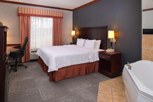 um quarto de hotel com uma cama e uma banheira em Hampton Inn & Suites Greenville em Greenville