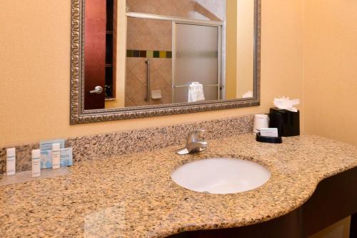 Hampton Inn & Suites Greenville في غرينفيل: منضدة الحمام مع الحوض والمرآة