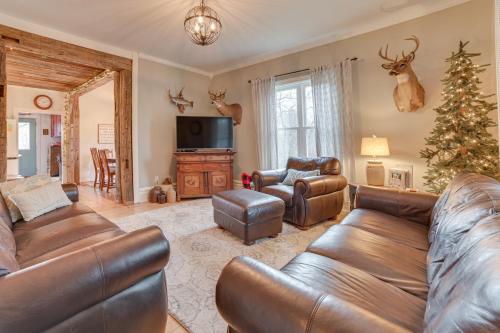 a living room with a leather couch and a christmas tree at Cedar Creek Guesthouse 3 Mi to Lake Charlevoix in East Jordan