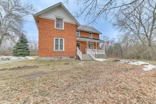 a red brick house with a porch on a yard at Cedar Creek Guesthouse 3 Mi to Lake Charlevoix in East Jordan