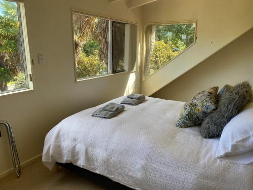a bedroom with a white bed with three windows at Oneroa Chalet in Oneroa