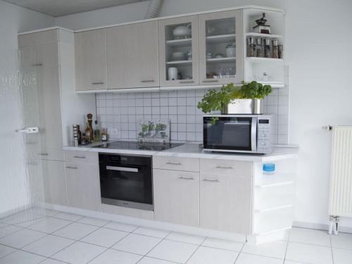 uma cozinha com armários brancos e um micro-ondas em Holiday apartment Taunustraum in Hohenstein Hesse 