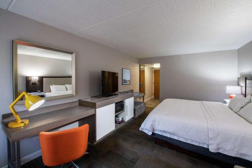 a hotel room with a bed and a desk with a mirror at Hampton Inn Gainesville in Gainesville