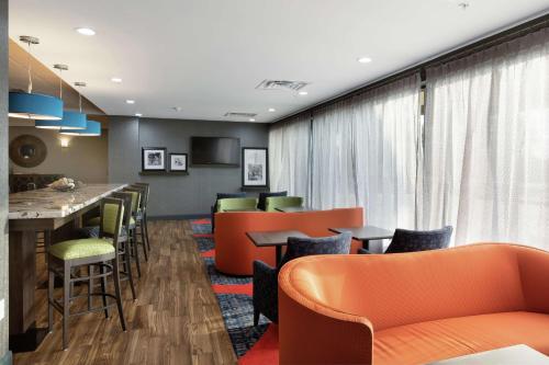 a waiting room with orange chairs and a bar at Hampton Inn Houston/Humble-Airport Area in Humble