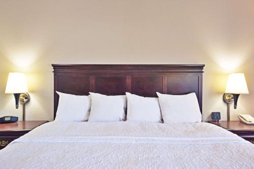 a bedroom with a bed with white pillows and two lamps at Hampton Inn Huntington/Barboursville in Barboursville