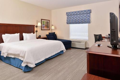 a hotel room with a bed and a flat screen tv at Hampton Inn Harrisonburg South in Harrisonburg