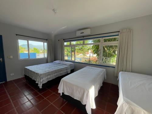 um quarto com 2 camas e uma grande janela em Pousada Praiamar em São Sebastião