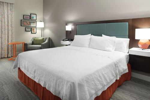 a hotel room with a large bed and a chair at Hampton Inn Jasper in Jasper