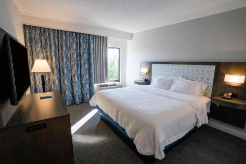 a hotel room with a bed and a flat screen tv at Hampton Inn & Suites Fairfield in Fairfield