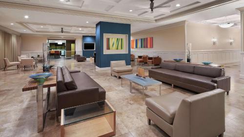 DoubleTree by Hilton Sunrise - Sawgrass Mills في صنرايز: غرفة معيشة مع كنب وطاولات وكراسي