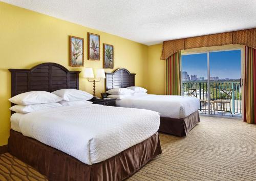 a hotel room with two beds and a balcony at Embassy Suites by Hilton Fort Lauderdale 17th Street in Fort Lauderdale