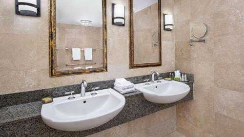 a bathroom with two sinks and two mirrors at DoubleTree by Hilton Sunrise - Sawgrass Mills in Sunrise