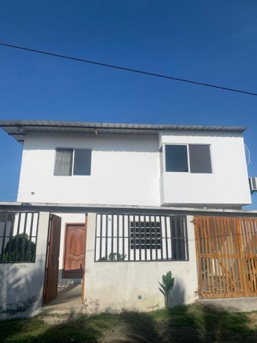 una casa blanca con una puerta y una valla en Casa San Jacinto, en Rocafuerte