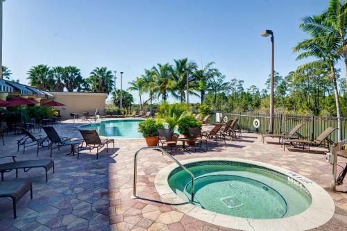 Embassy Suites Fort Myers - Estero في استيرو: مسبح مع كراسي وحوض استحمام ساخن