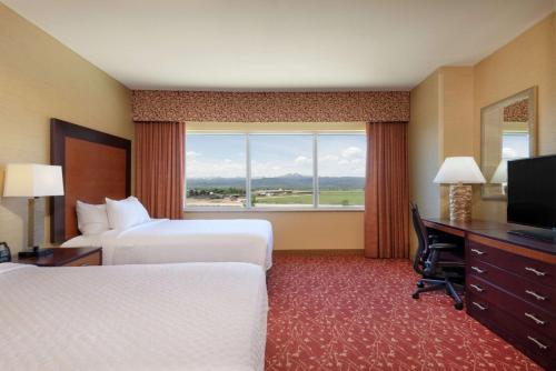 a hotel room with two beds and a desk and a window at Embassy Suites by Hilton Loveland Conference Center in Loveland