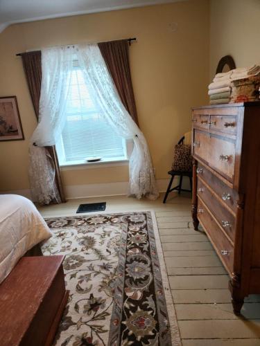 a bedroom with a bed and a dresser and a window at Stone Carriage House in Picton