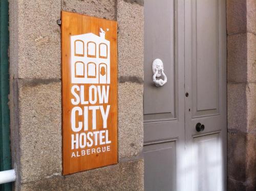 a sign on the side of a building next to a door at Slow City Hostel Pontevedra in Pontevedra