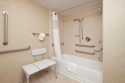 La salle de bains est pourvue d'une baignoire, d'une chaise et d'une douche. dans l'établissement Hampton Inn Indianapolis Northeast/Castleton, à Indianapolis