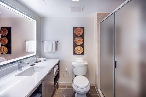 a bathroom with a toilet and a sink and a mirror at Embassy Suites by Hilton Houston-Energy Corridor in Houston