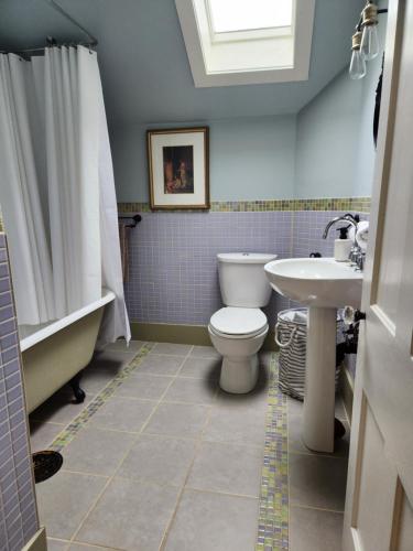 La salle de bains est pourvue de toilettes, d'une baignoire et d'un lavabo. dans l'établissement Stone Carriage House, à Picton