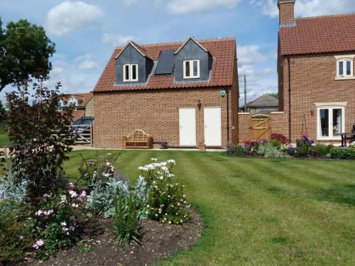 una casa de ladrillo con un patio con flores en Glen House Annexe, en Bourne