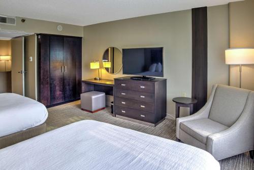 um quarto de hotel com uma cama e uma cadeira e uma televisão em Embassy Suites by Hilton Indianapolis North em Indianápolis