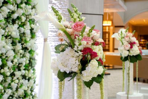 a row of vases filled with flowers on a table at Embassy Suites by Hilton Jacksonville Baymeadows in Jacksonville